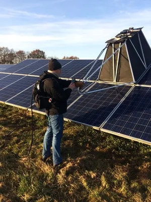 A man stands outside at a PV module and checks it with a tool