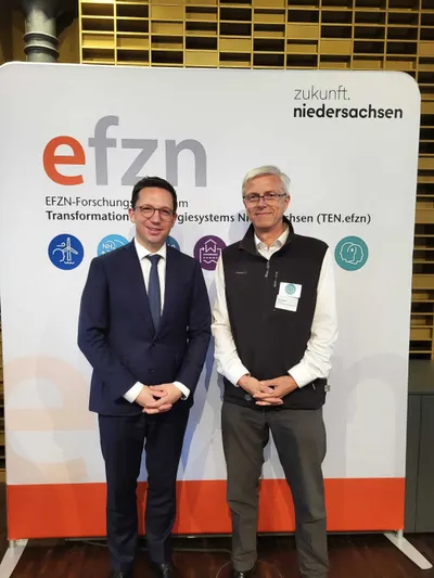 Falko Mohrs und Prof. Dr. Rolf Brendel stehen vor einem Info-Aufsteller vom EFZN-Forschungszentrum
