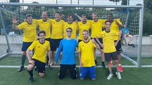 Gruppenfoto des Fußballteams in gelben Trikots vor einem Fußballtor