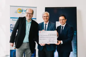 Portrait von drei Männern mit einem unterzeichneten Förderbescheid in der Hand