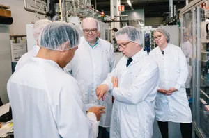 Mehrere Personen in Laborkleidung stehen in einem Labor und schauen sich einen Gegenstand an
