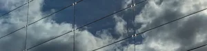 Eine Solarfassade, in der sich der blaue Himmel mit Wolken spiegelt