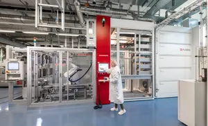 Eine Mitarbeiterin bedient eine industrielle PECVD-Beschichtungsanlage.