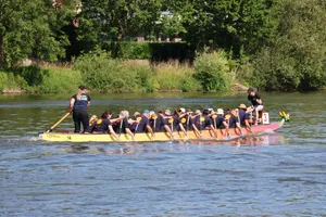 Das SIFH Drachenboot-Team paddelt auf der Weser. Am Heck steht eine Steuerfrau, vorne sitzt eine Trommlerin.