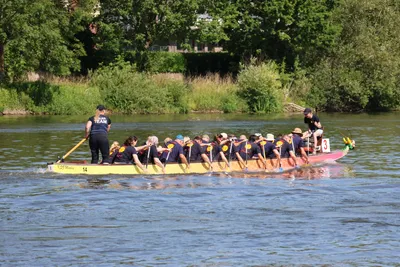Das SIFH Drachenboot-Team paddelt auf der Weser. Am Heck steht eine Steuerfrau, vorne sitzt eine Trommlerin.